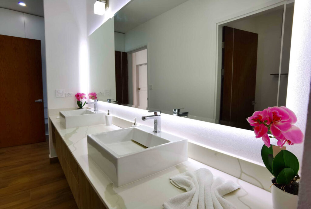 This gorgeous master bathroom features beautiful his and hers porcelain sinks in front of a huge mirror.