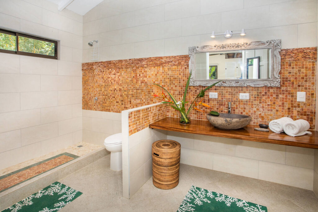 This stunning bathroom features natural tiles, a wooden counter top, and a natural stone sink.