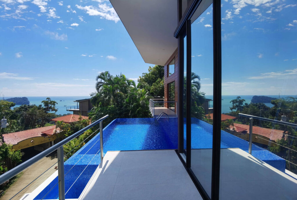 Giant sliding doors open to the balcony, stunning infinity pool, and the gorgeous Manuel Antonio view.