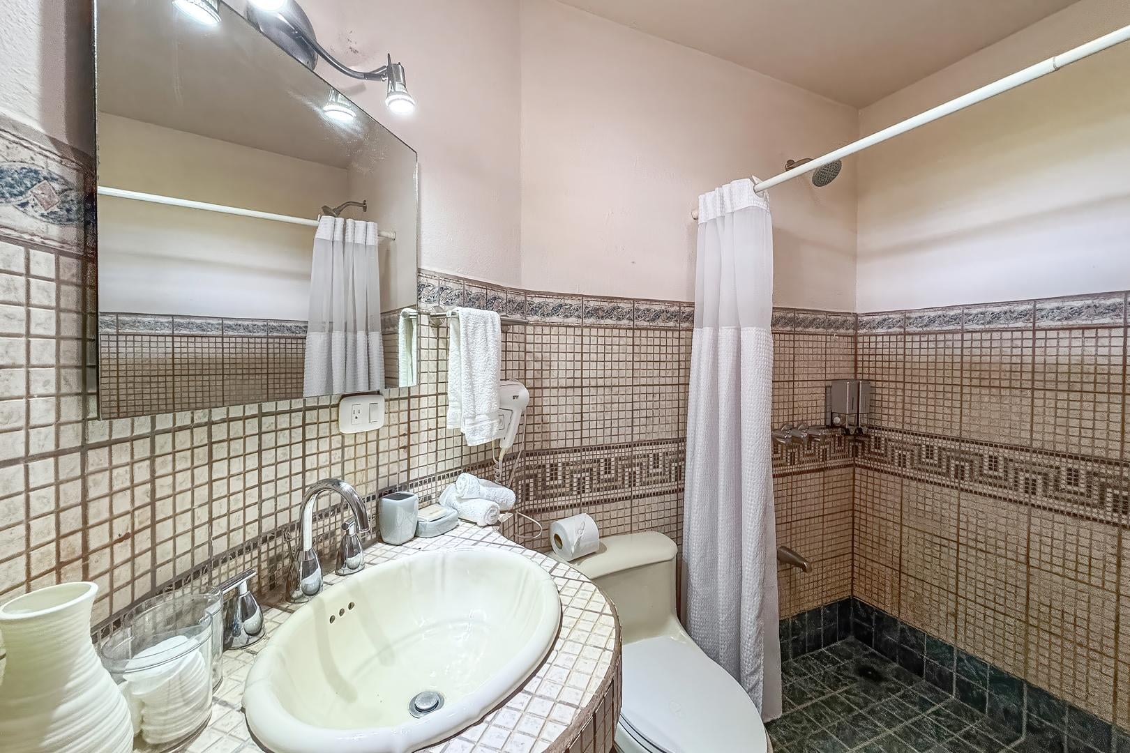 Ensuite bathroom with tiled shower, sink, mirror, and neutral finishes