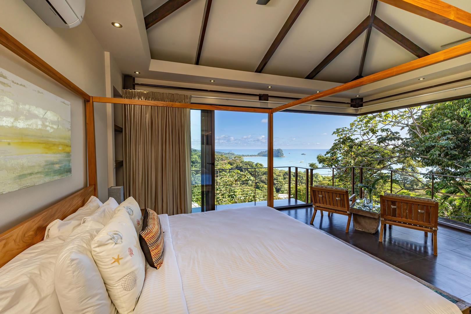 Bedroom with sliding glass doors opening to jungle and Pacific Ocean views
