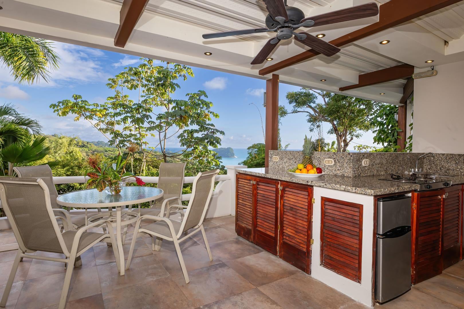 Covered terrace with outdoor kitchen, dining area, and ocean views accessed from a twin bedroom