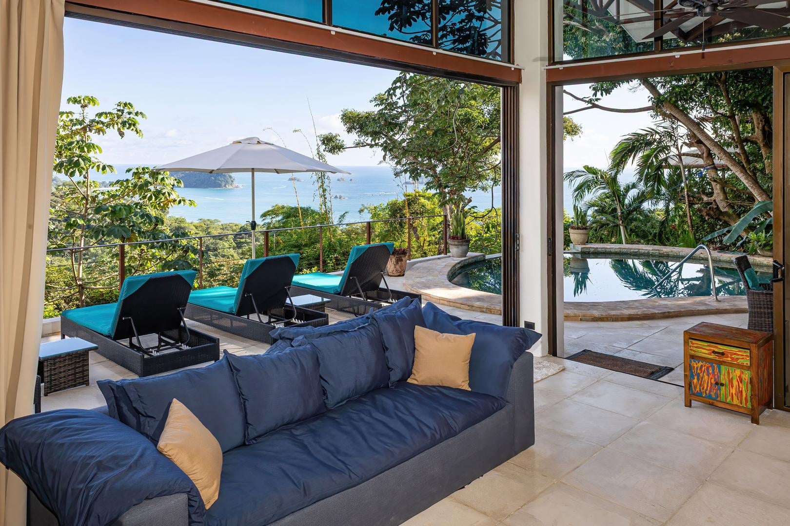 Open living area leading to a pool terrace with ocean views and tropical surroundings in Manuel Antonio