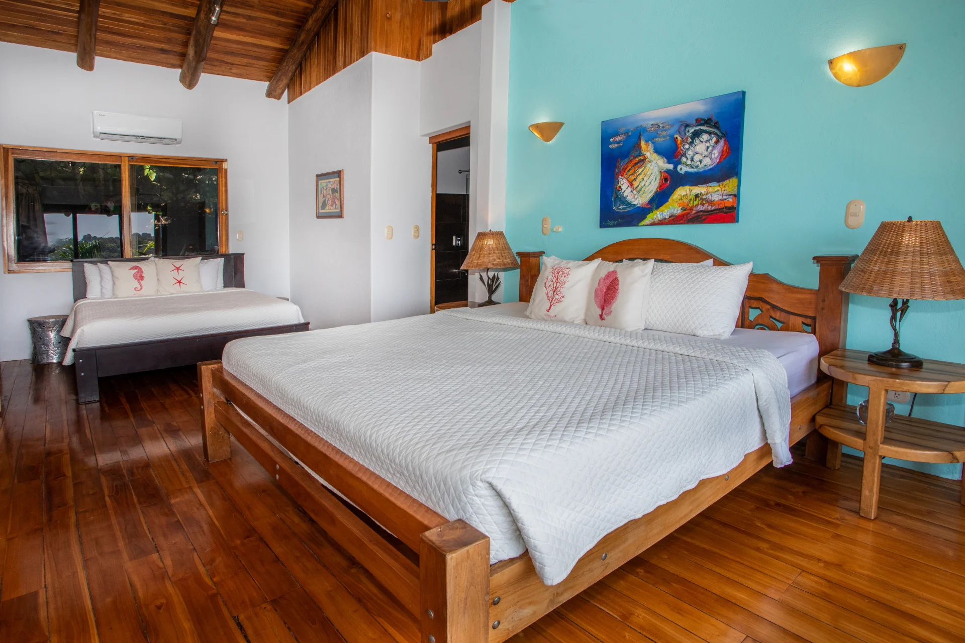 Twin bedroom with two beds, wooden floors, coastal artwork, and natural light