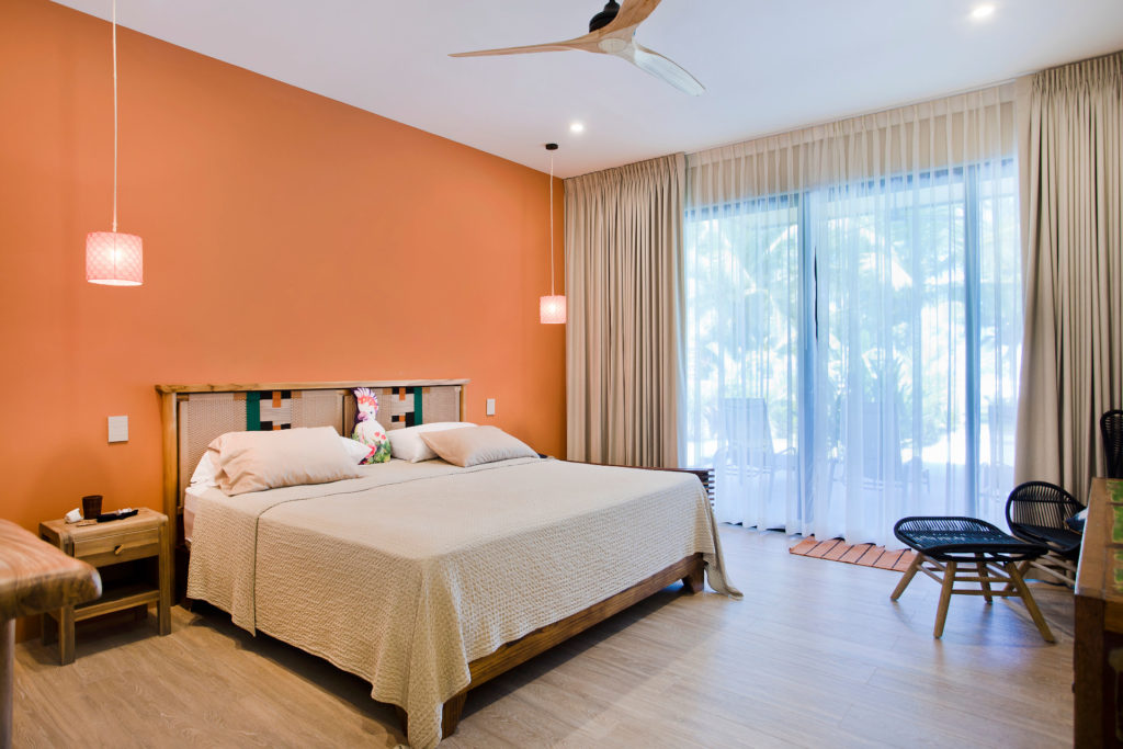 Experience luxury in our fully-airconditioned master bedroom featuring a king-size bed and a view of the beach and tropical gardens.