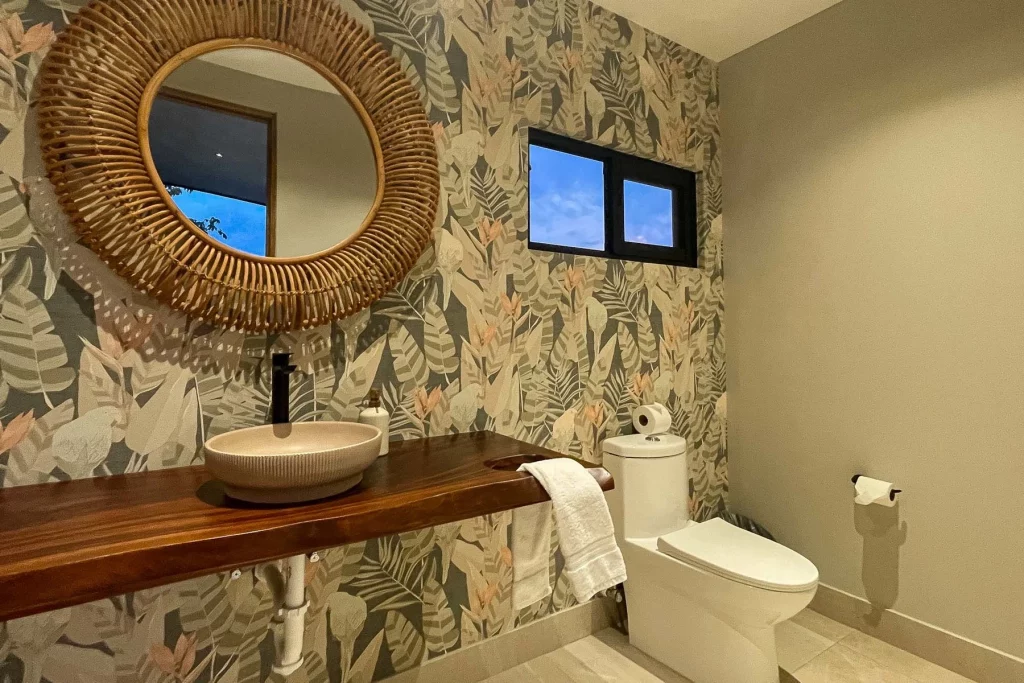 Exotic wallpaper, a natural wood counter, and other tropical details decorate this lovely bathroom.