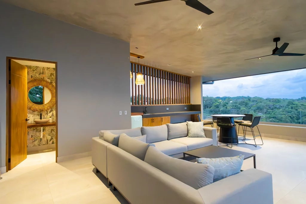 The neutral colors of this tasteful sitting area contrast with the vibrant greens of the distant rainforest.