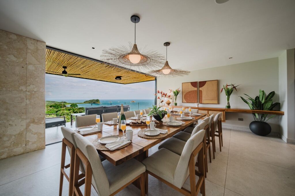 The table sits just inside the view, where meals unfold with the ocean beyond.