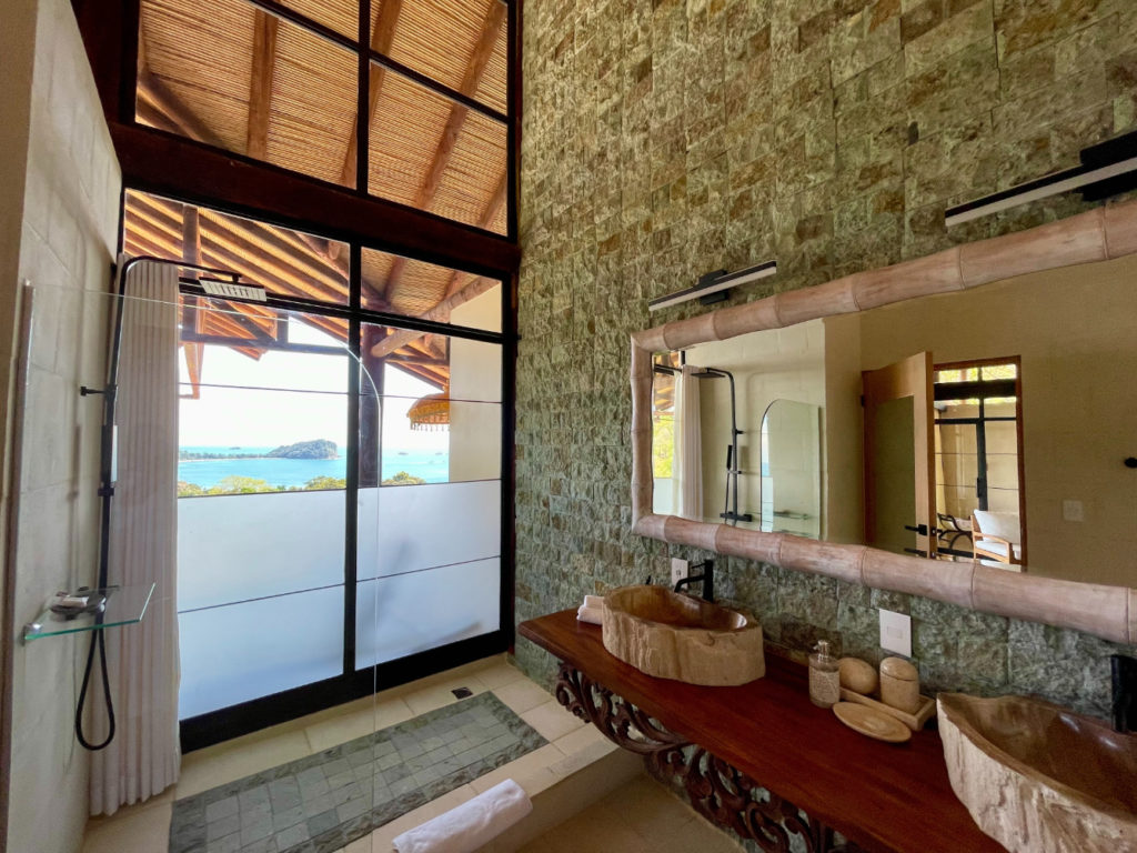 A bathroom of extraordinary distinction, showcasing remarkable design elements, with floor to ceiling glass windows that offer stunning ocean views.