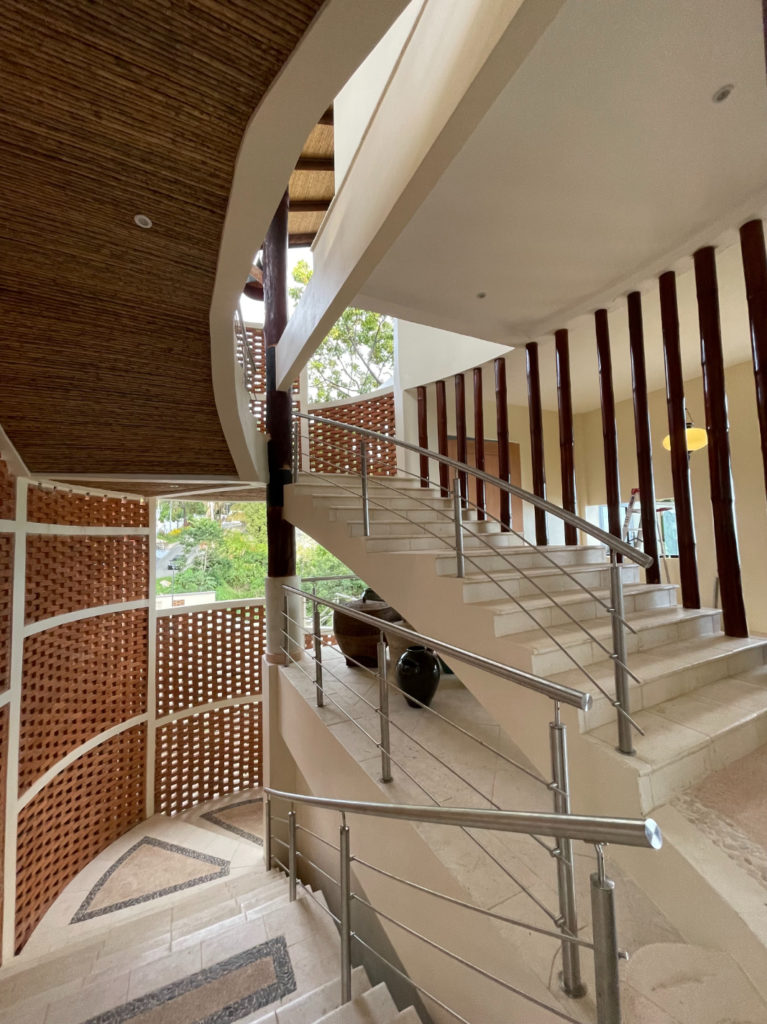The staircase features a remarkable design, seamlessly merging modern stainless steel with the organic textures of natural woods, bricks, and stone accents.