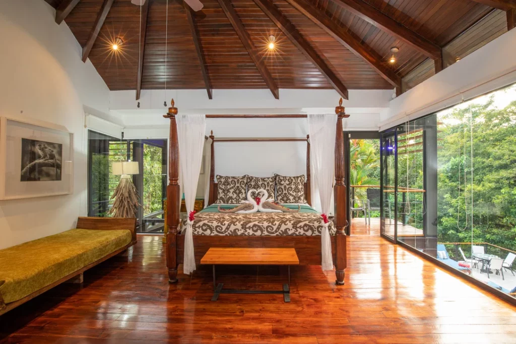 This opulent master bedroom boasts stunning wooden features such as a king-size poster bed, vaulted ceilings, and elegant wooden floors.