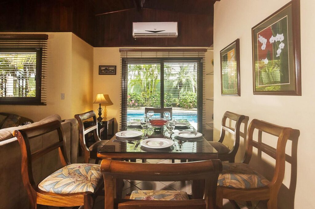 This large luxurious dining table seats six guests comfortably with sliding glass doors and a view to the pool.