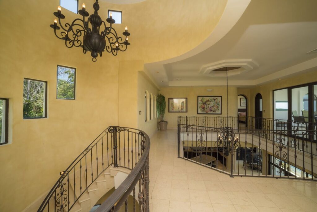 The upper-level gallery is a showpiece, enhanced by dramatic chandeliers throughout the home.