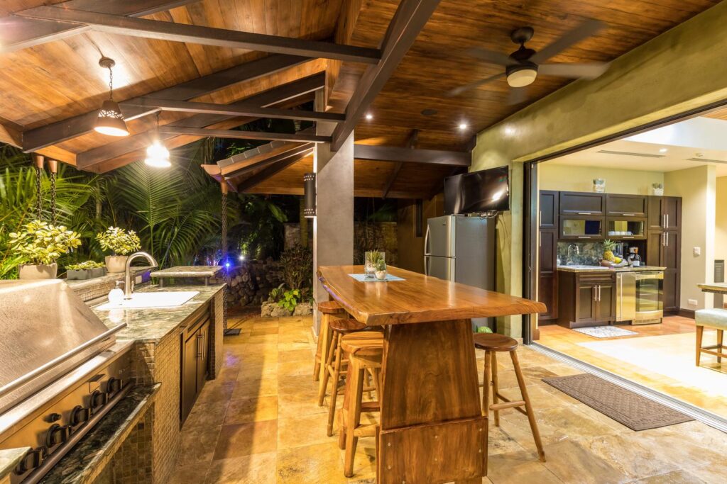 Outdoor kitchen and bar designed with natural wood, stone finishes, and warm ambient.