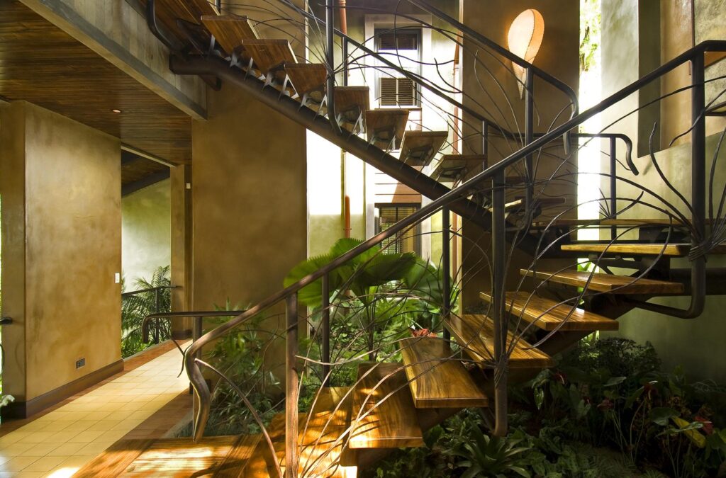 Artistry in motion — sculpted iron and wood connect each level through an exotic indoor garden.