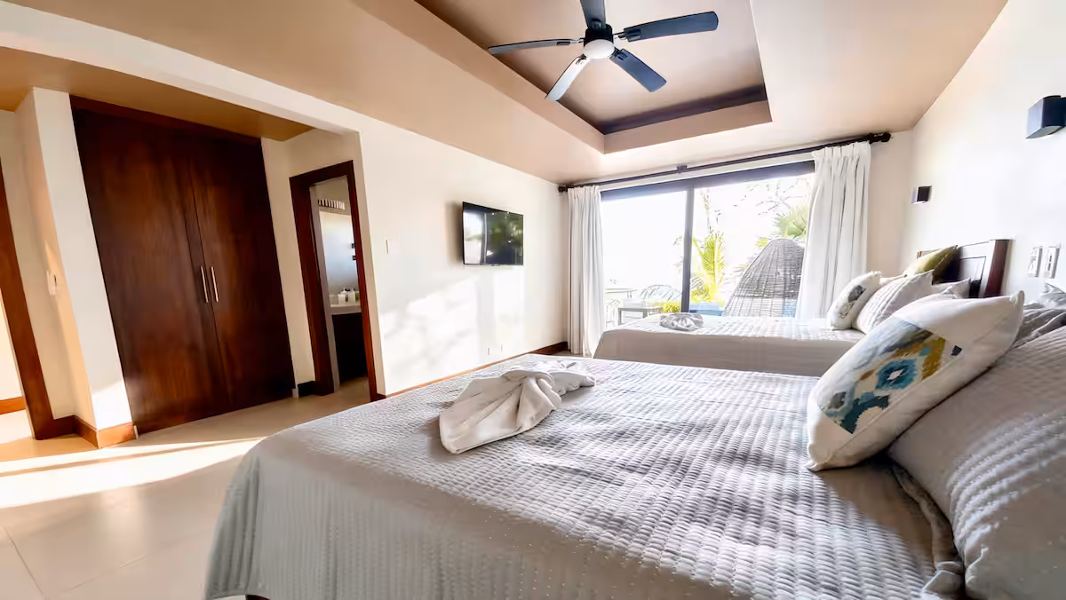 Guest bedroom with two queen beds and ocean-view balcony in a Costa Rica luxury beachfront villa