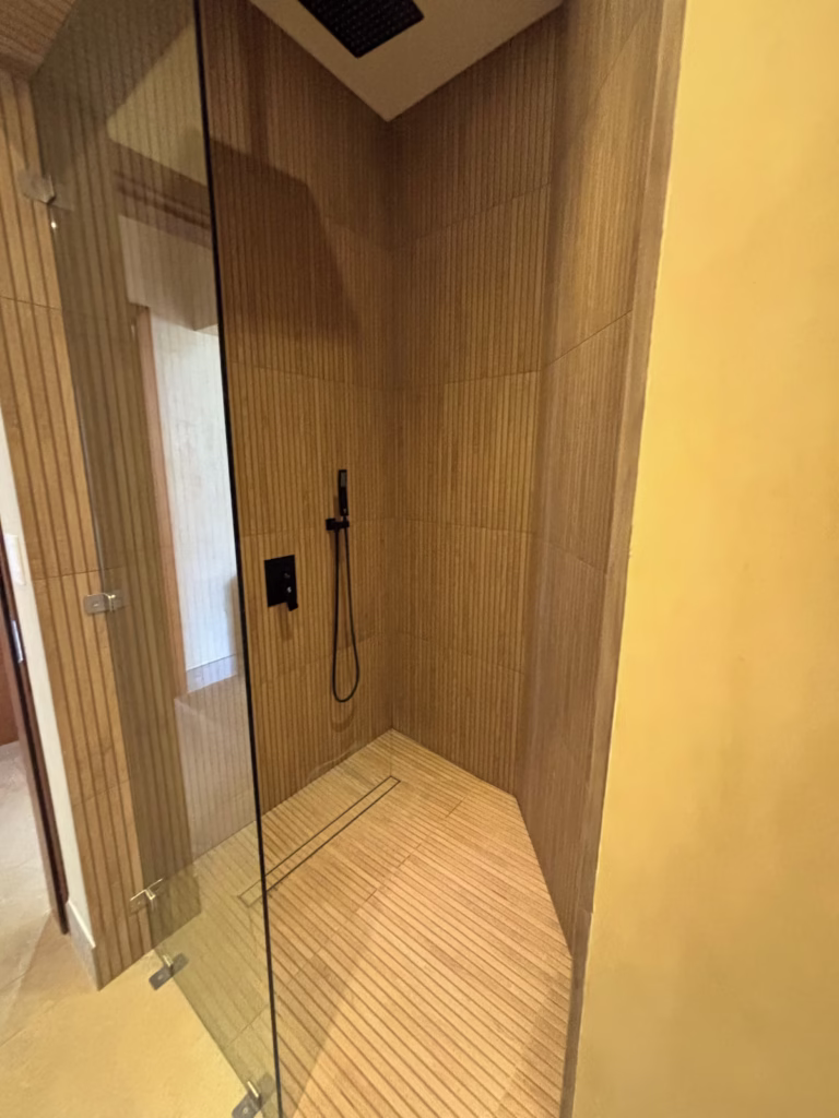 The modern walk-in shower features a rainfall showerhead, floor-to-ceiling tile, and sleek contemporary finishes.