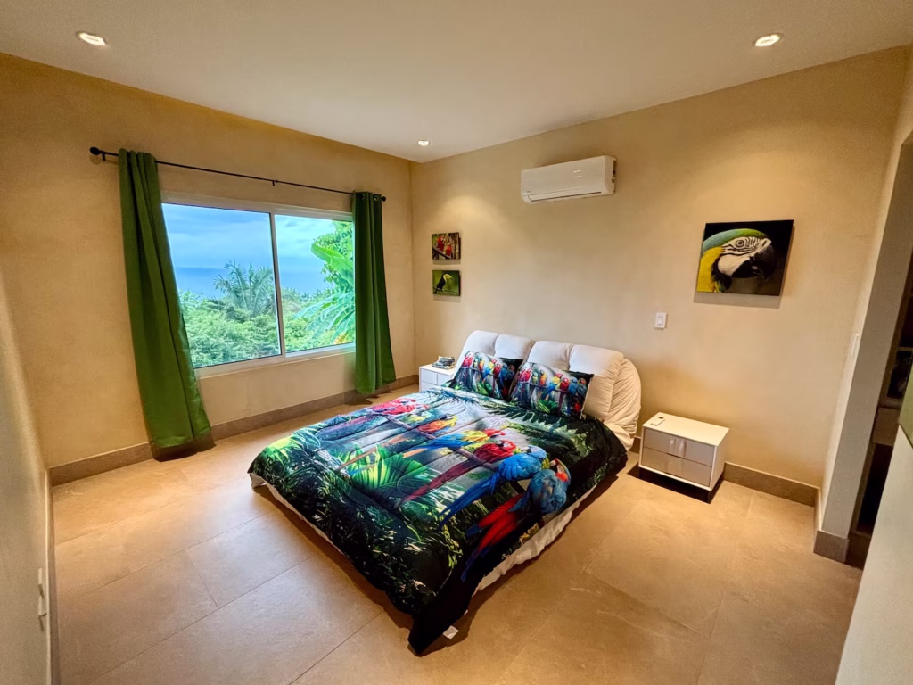 A colorful macaw-inspired bedroom with Pacific Ocean views offers a cheerful and comfortable retreat for families exploring Costa Rica.