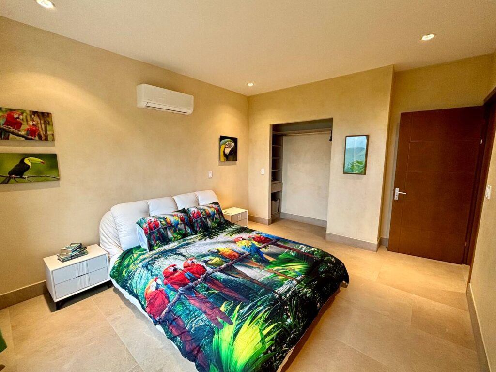 A colorful macaw-themed bedroom with ocean views creates a cheerful and comfortable retreat for families vacationing in Costa Rica.