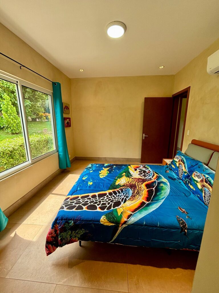 A bright guest bedroom with colorful sea turtle décor and peaceful garden views creates a relaxing retreat for every stay.